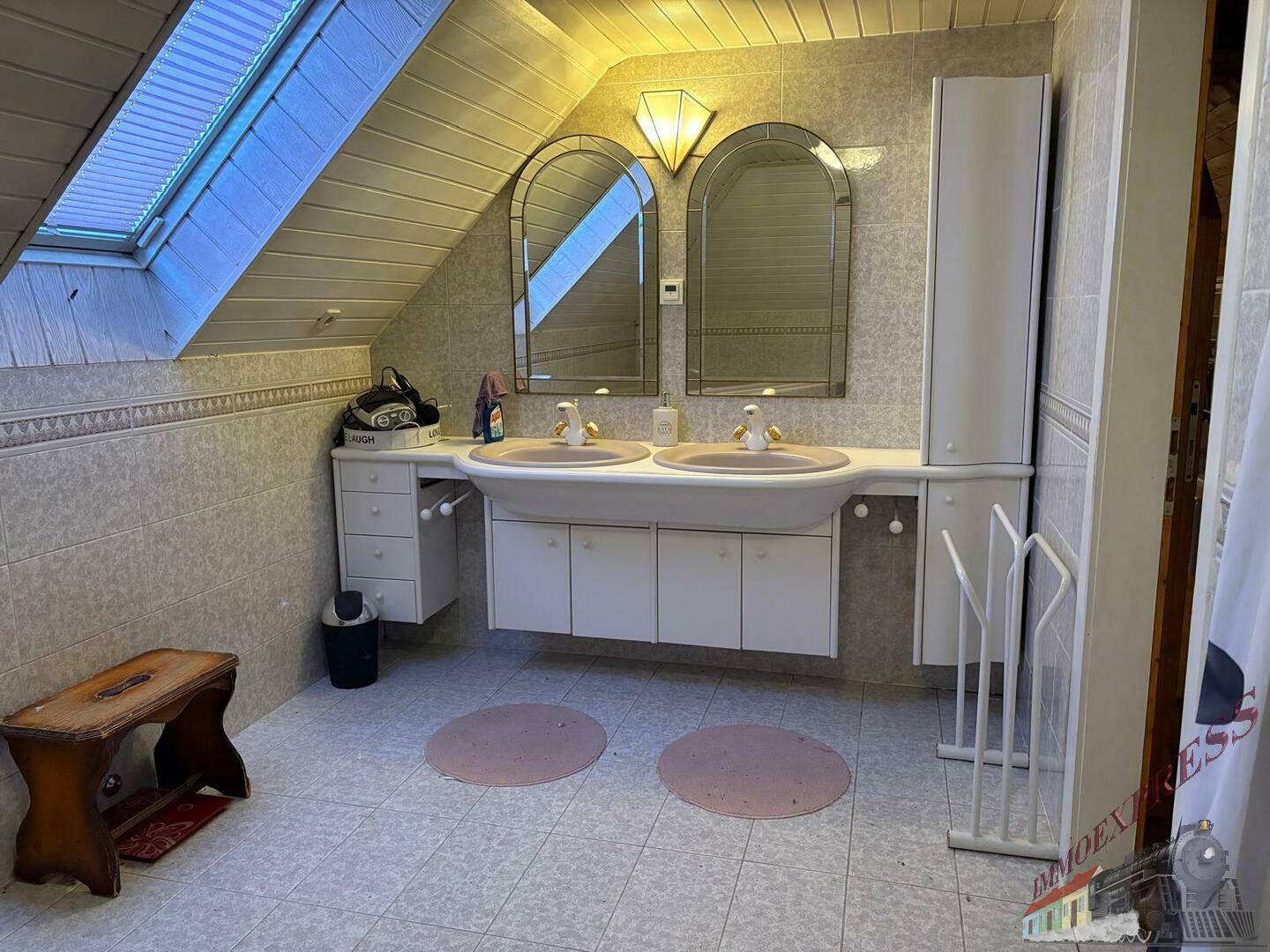 Dachgeschoss-Badezimmer mit Doppelwaschbecken, Dachfenster und Holzdeckenverkleidung.
