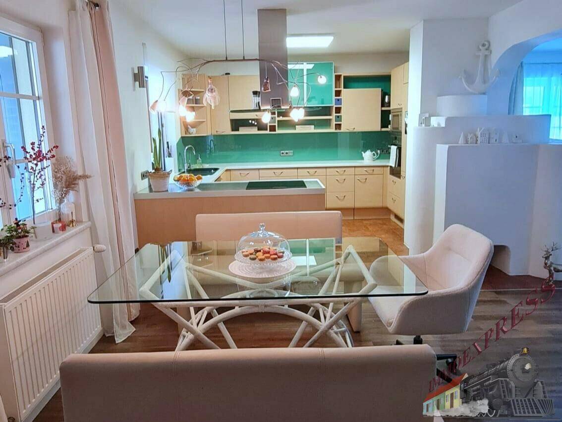 Offener Wohn- und Essbereich mit moderner Küche, Glas-Esstisch und hellem Holzboden.