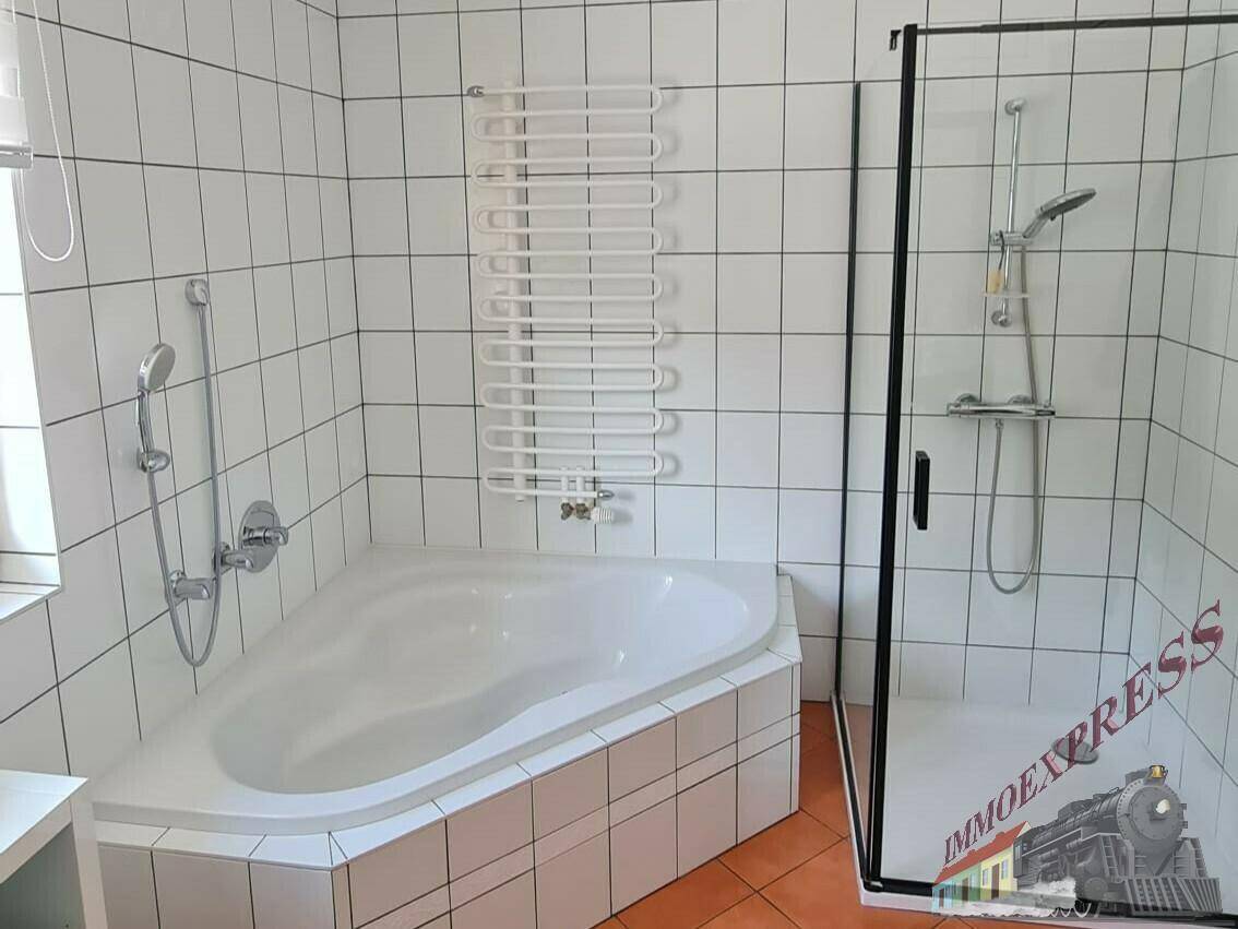 Modernes Badezimmer mit Eckbadewanne, Duschkabine und weiß gefliesten Wänden.