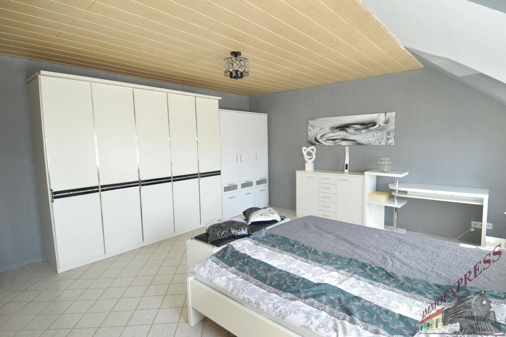 Schlafzimmer im Dachgeschoss mit großem Kleiderschrank, Doppelbett und Dachschrägen.