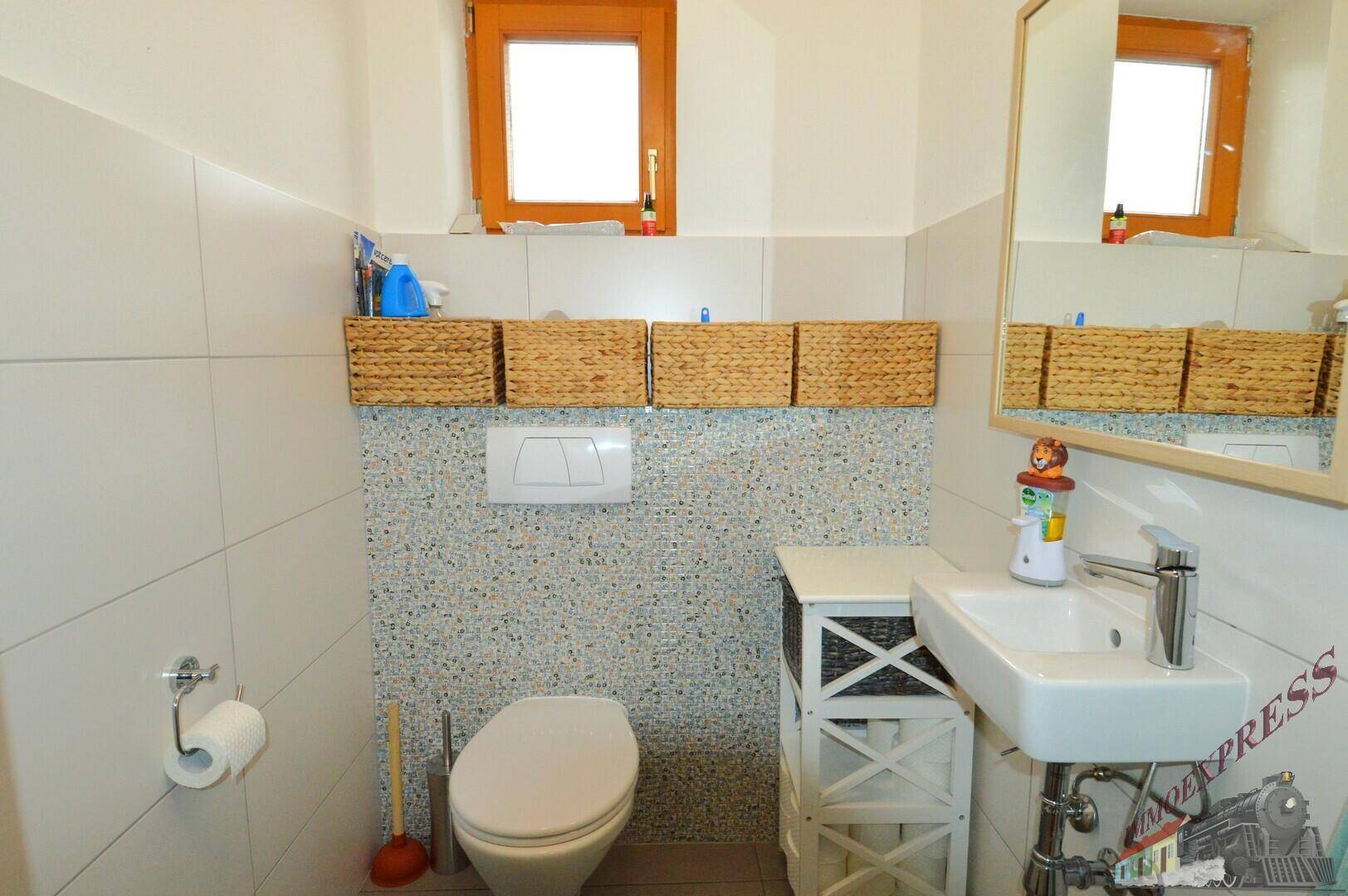 Modernes Gäste-WC mit Wand-WC, kleinem Waschbecken und Fenster, praktisch und hell.