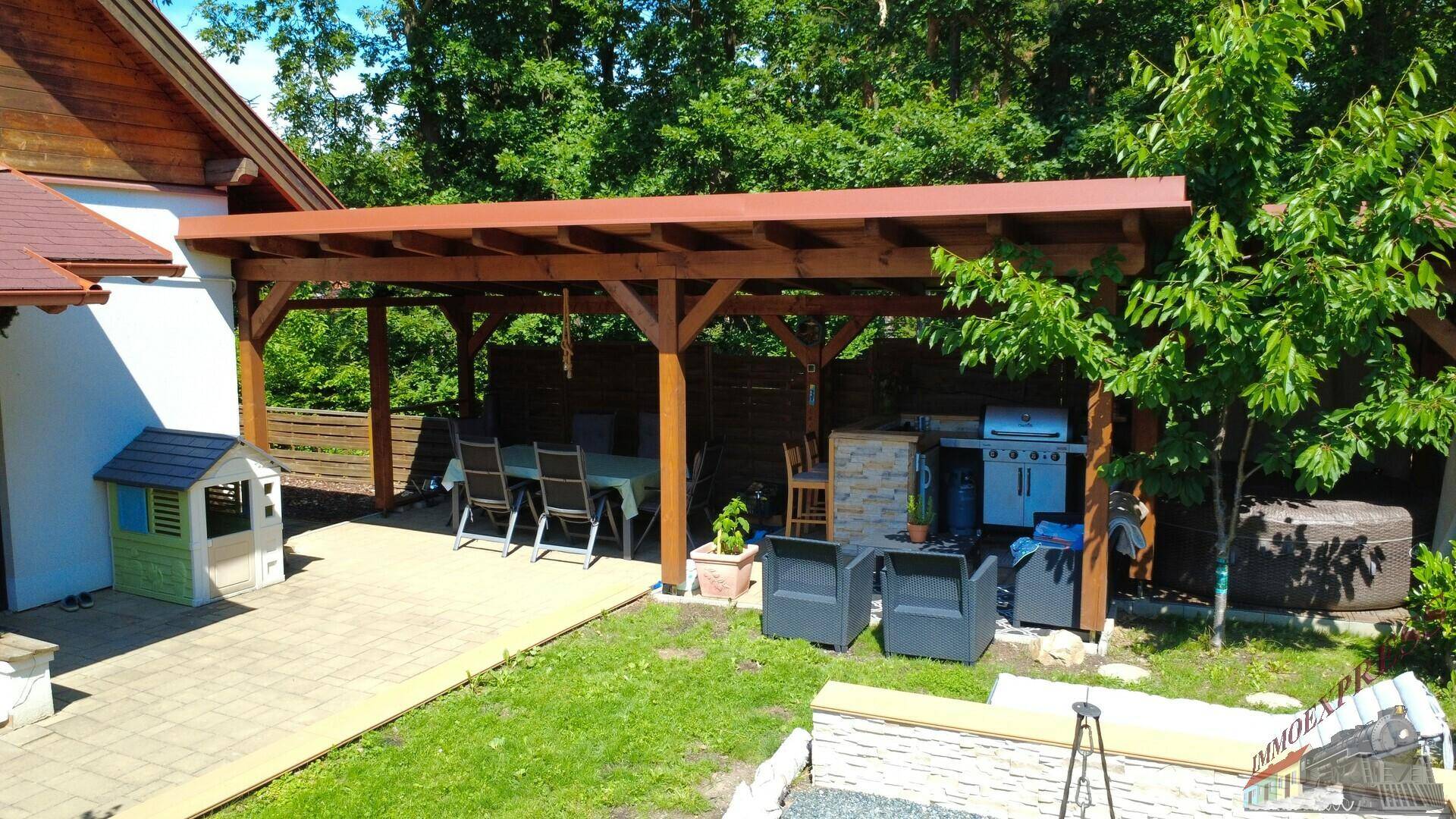 Überdachte Terrasse mit Esstisch, Grillbereich und direktem Zugang zum Garten für gesellige Stunden.