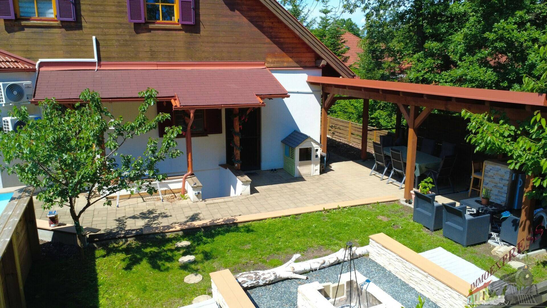 Gartenbereich mit überdachter Terrasse, Feuerstelle und Zugang zum Haus.