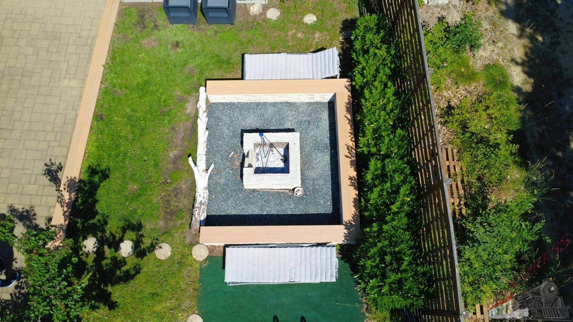 Blick von oben auf den gepflegten Gartenbereich mit Feuerstelle und Sitzgelegenheiten.