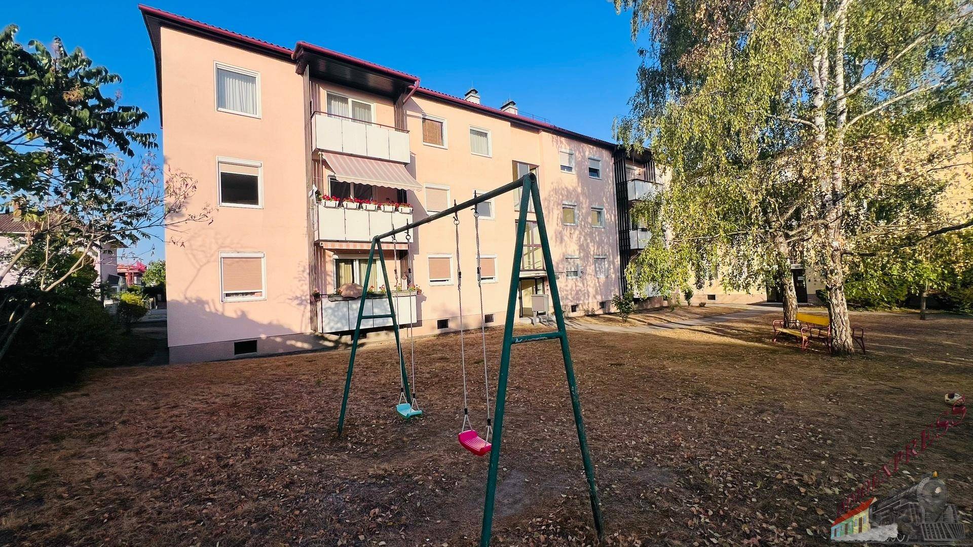 Außenansicht des Gebäudes mit Kinderschaukel im Vordergrund und großem Gartenbereich.