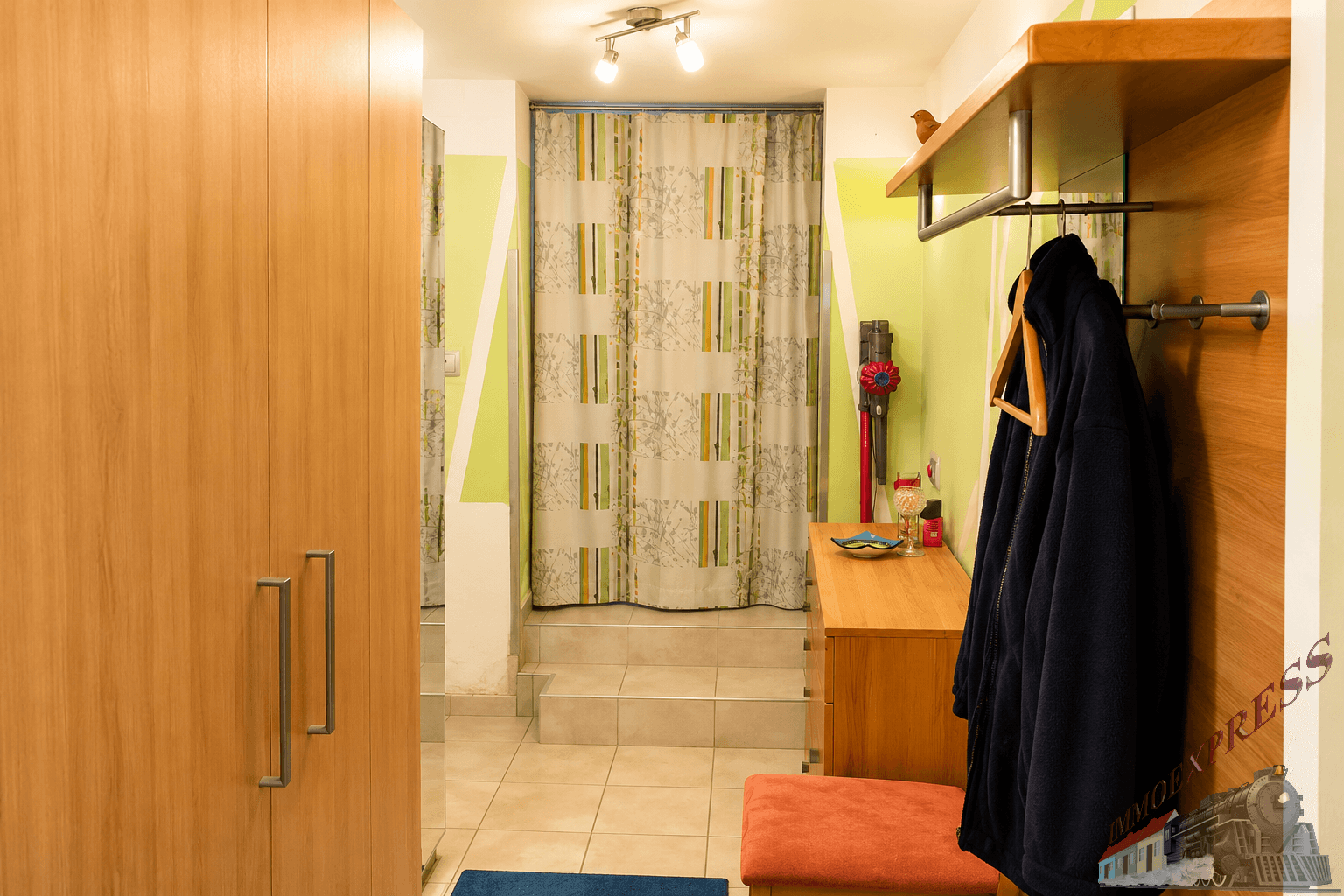 Eingangsbereich mit Holzschrank, Garderobe und Stufen zu einem weiteren Bereich.
