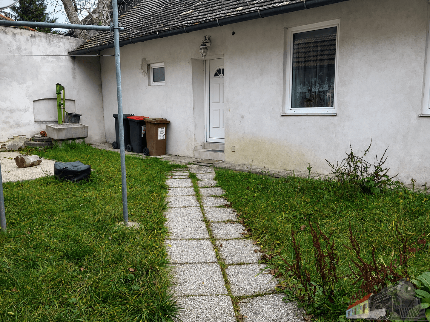 Einfacher Gartenbereich mit gepflastertem Weg, Rasenfläche und Hinterhofatmosphäre.