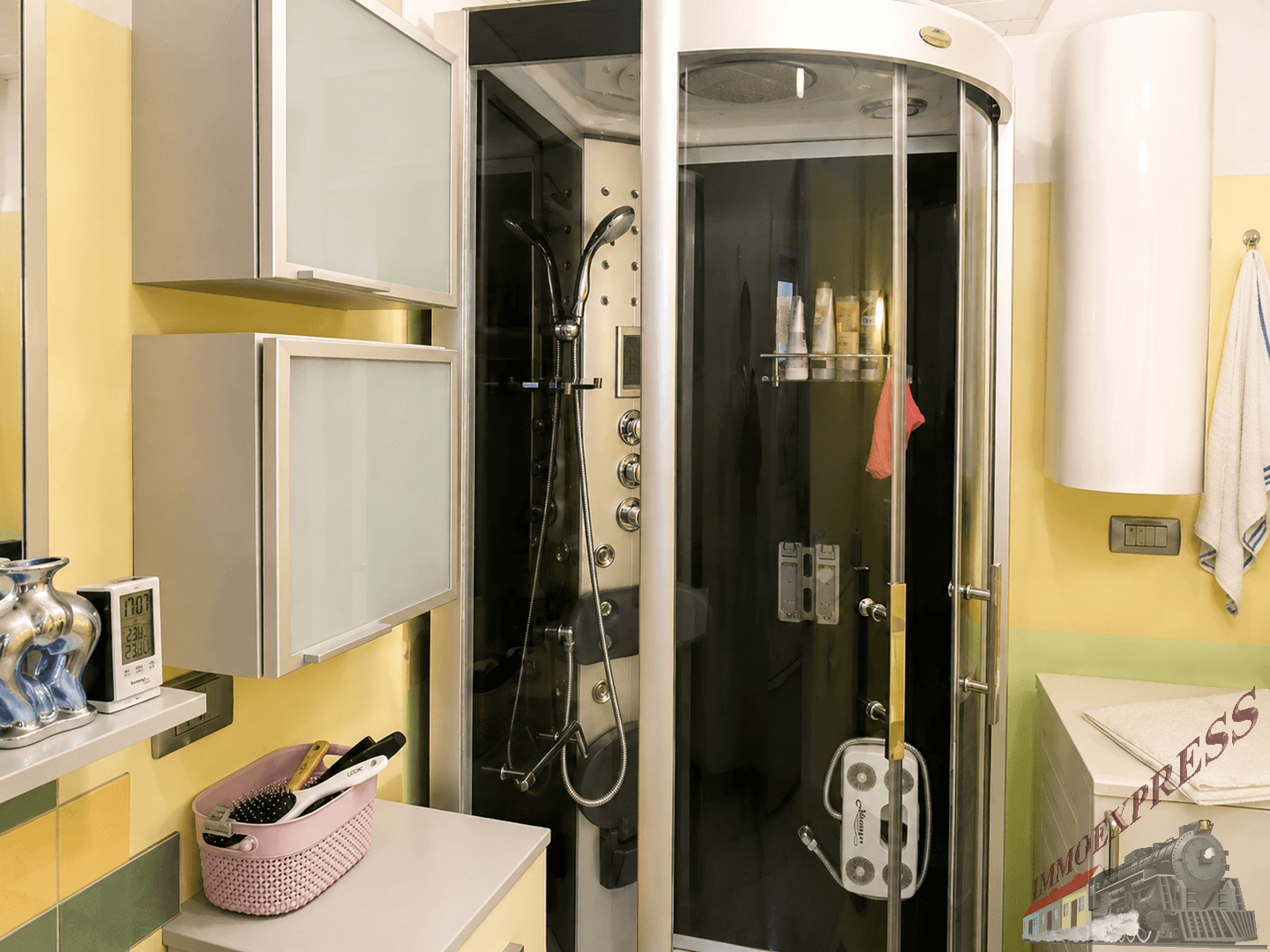 Badezimmer mit moderner Duschkabine, gelben Wänden und grünen Akzentfliesen.