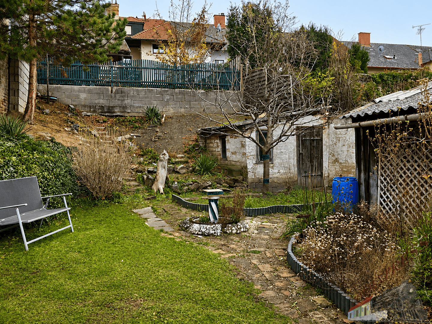 Garten mit Rasenfläche, alten Bäumen und einem kleinen Nebengebäude im Hintergrund.