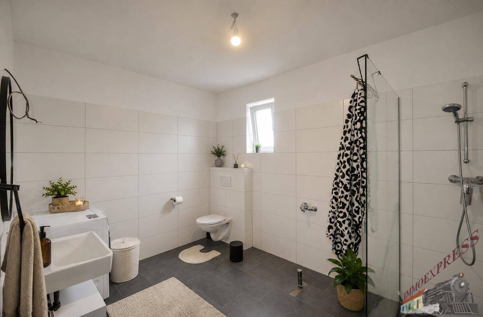 Geräumiges Badezimmer mit ebenerdiger Dusche, WC, Waschbecken und Waschmaschine.