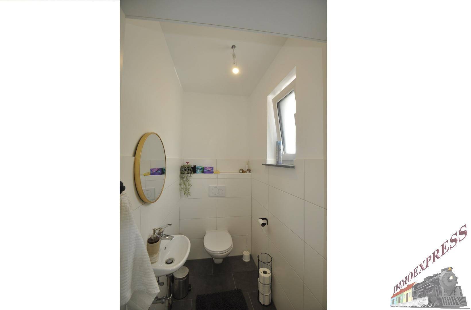 Helles Gäste-WC mit kleinem Waschbecken, Toilette und Fenster.