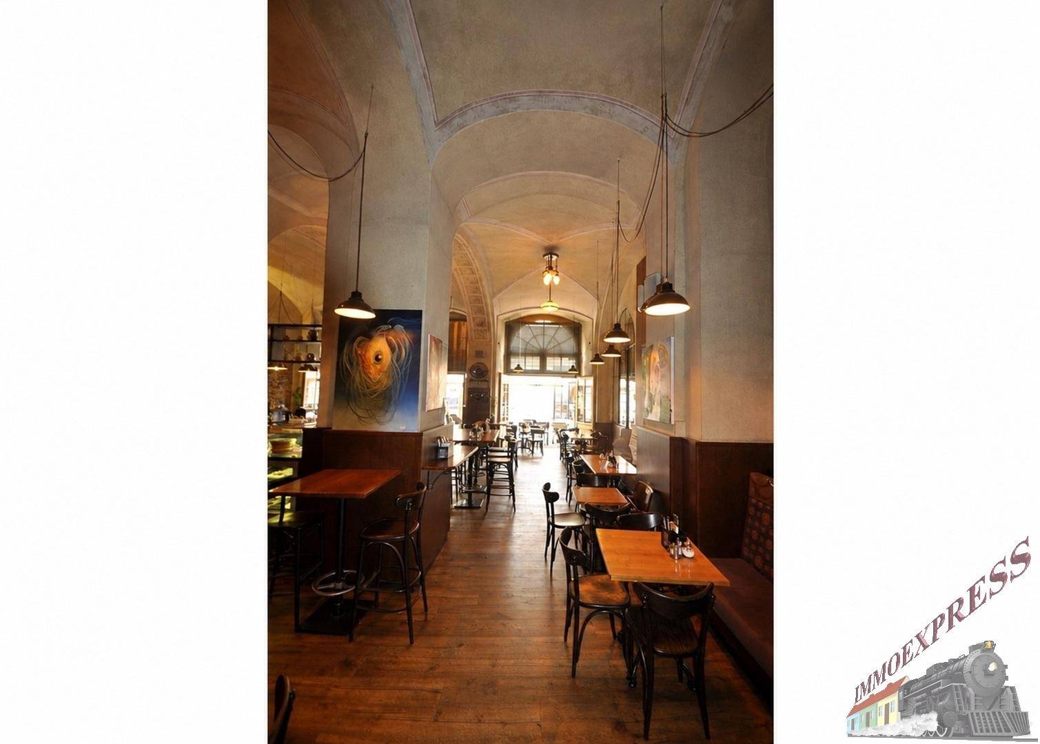 Langer Restaurantflur mit Holzböden, hohen Decken und Blick auf den Eingangsbereich.