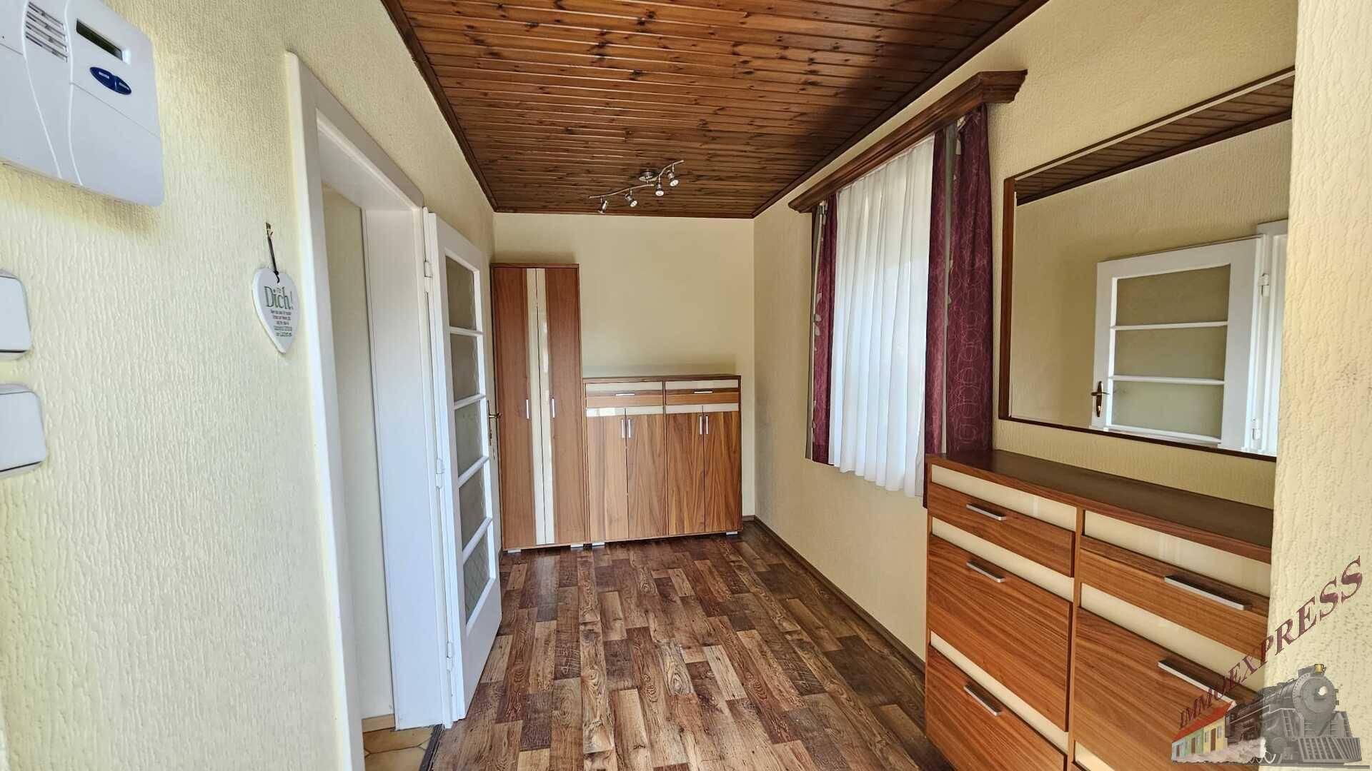 Zimmer mit Holzdecke, Laminatboden und Schrankmöbeln, ideal als Büro oder Gästezimmer.