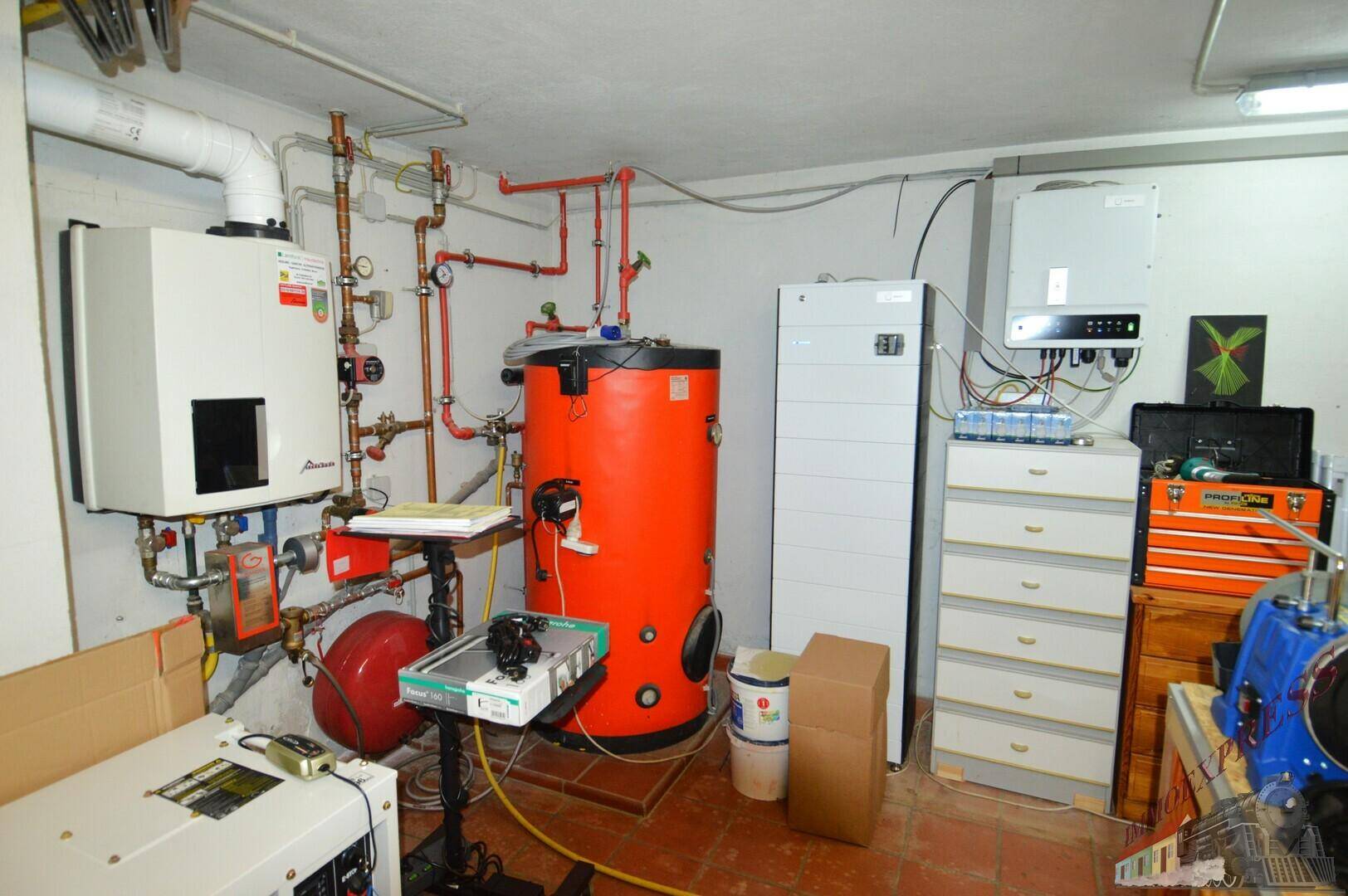 Technikraum mit Heizungsanlage, Warmwasserspeicher und elektrischen Installationen für das Haus.