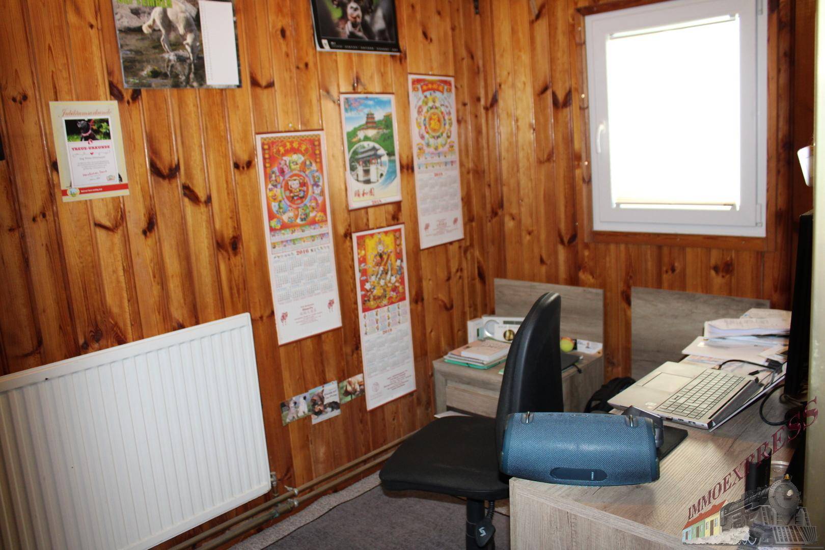 Arbeitsbereich mit Holzvertäfelung, Schreibtisch und Fenster, bietet eine ruhige Arbeitsatmosphäre.