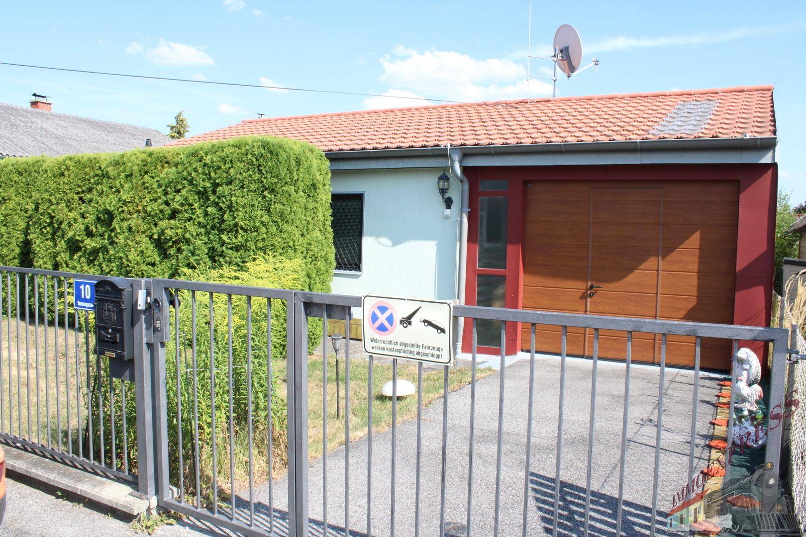 Vorderansicht des Hauses mit Zaun, Briefkasten und gepflegter Hecke im Vorgarten.