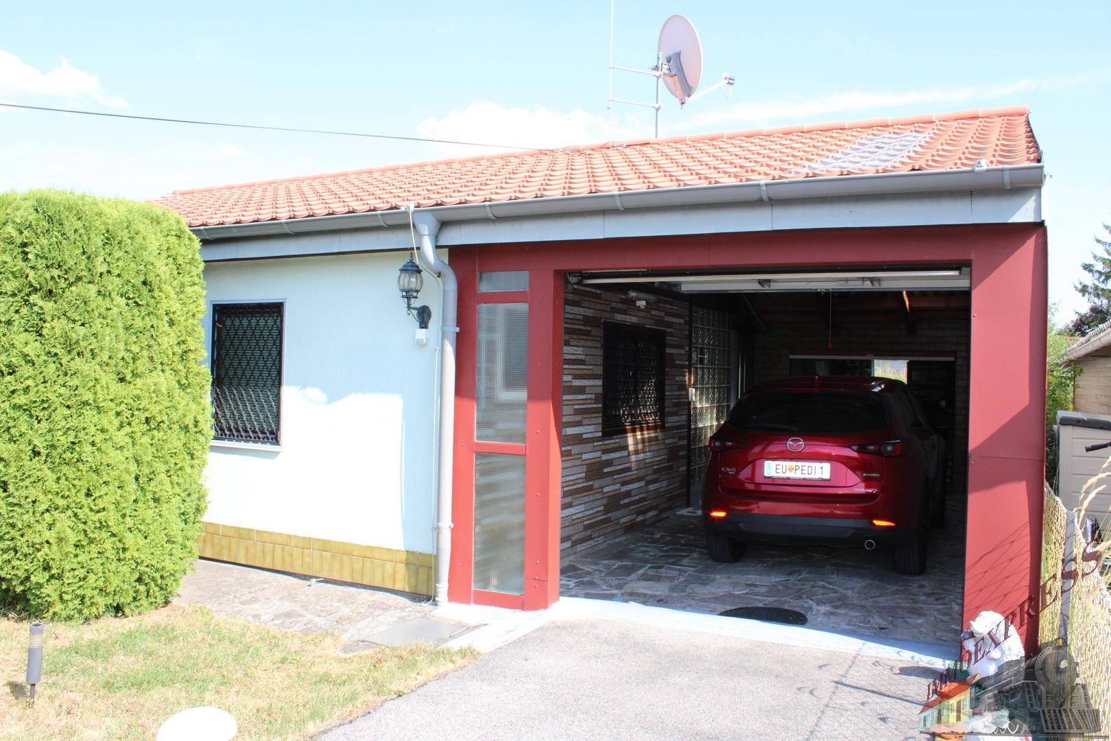 Offene Garage mit geparktem Auto, bietet Schutz und direkten Zugang zum Haus.