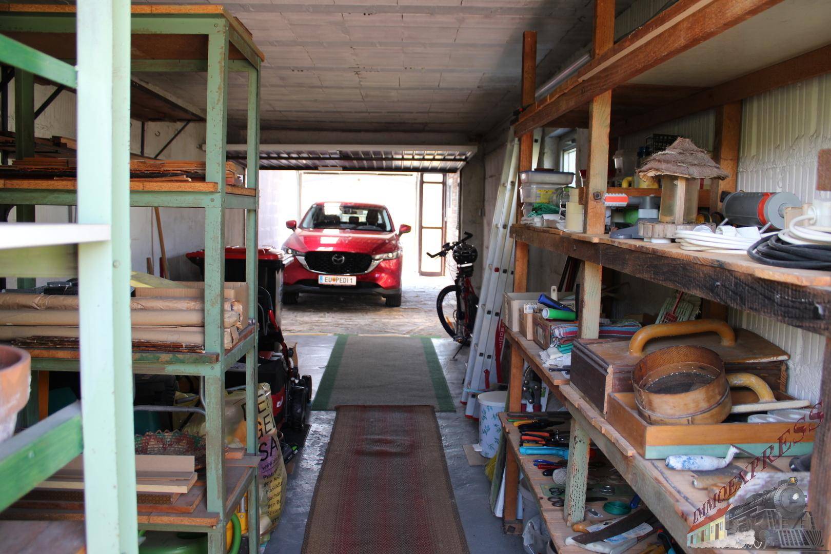 Geräumige Garage mit Regalen für Lagerung und einem geparkten Auto, vielseitig nutzbar.