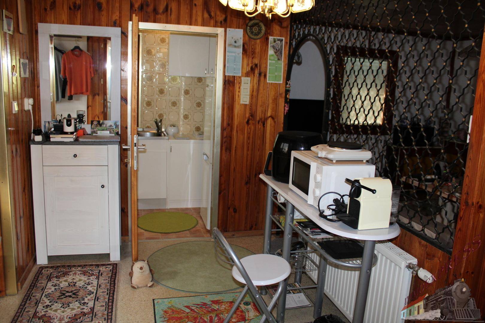 Flur mit Holzvertäfelung und Zugang zu einer kleinen Küchenzeile, praktisch und funktional.