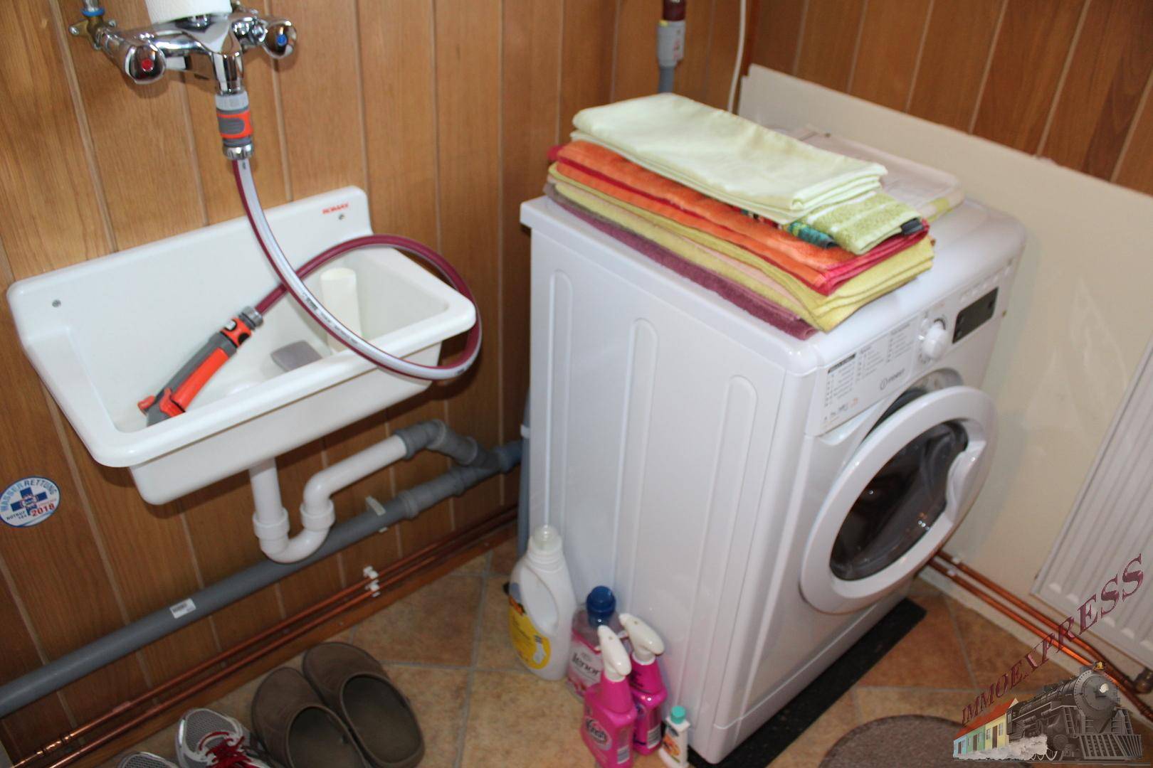 Praktischer Hauswirtschaftsraum mit Waschmaschine und Waschbecken, ideal für den täglichen Gebrauch.