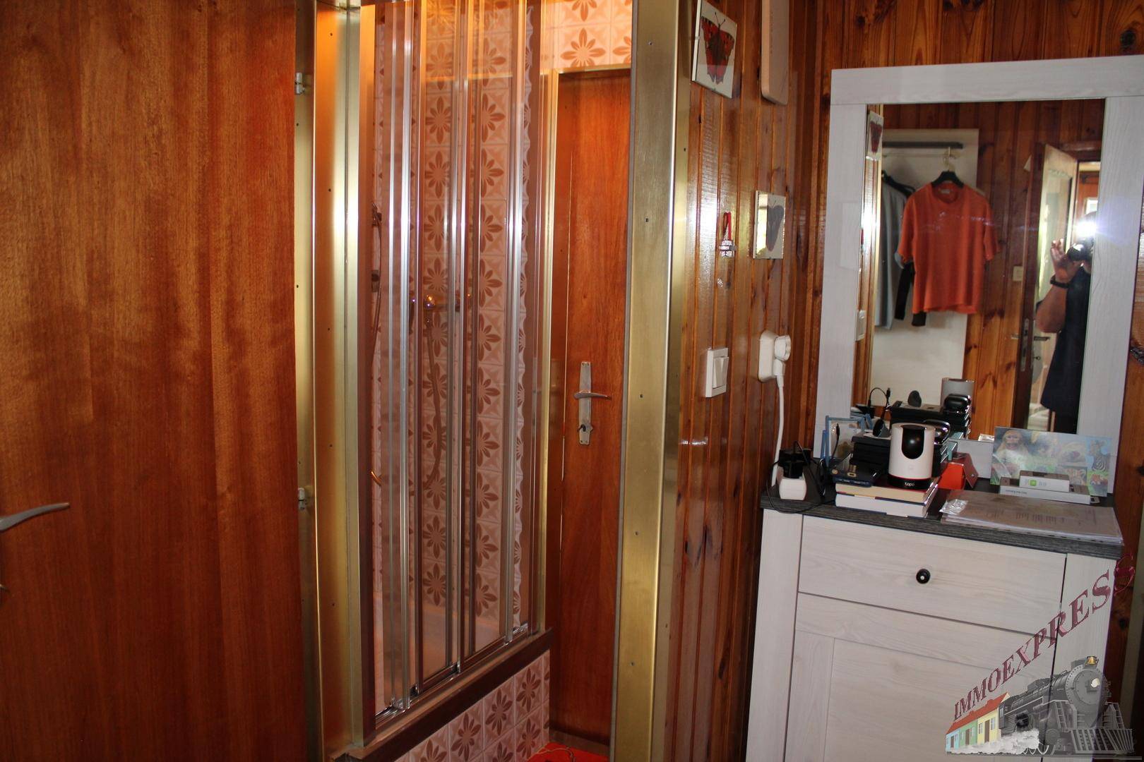 Kleines Badezimmer mit Holzvertäfelung und einer kompakten Duschkabine, funktional eingerichtet.