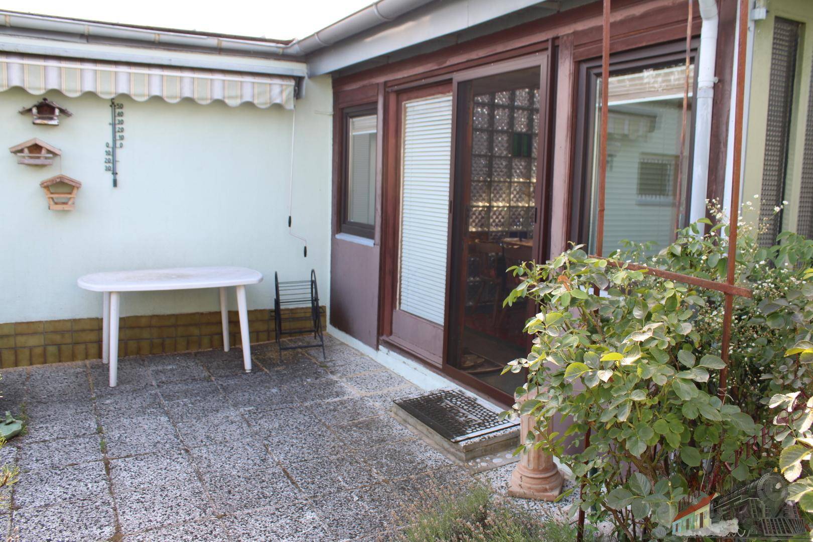 Gepflasterte Terrasse mit Gartenmöbeln und einer Markise, ideal für entspannte Stunden im Freien.