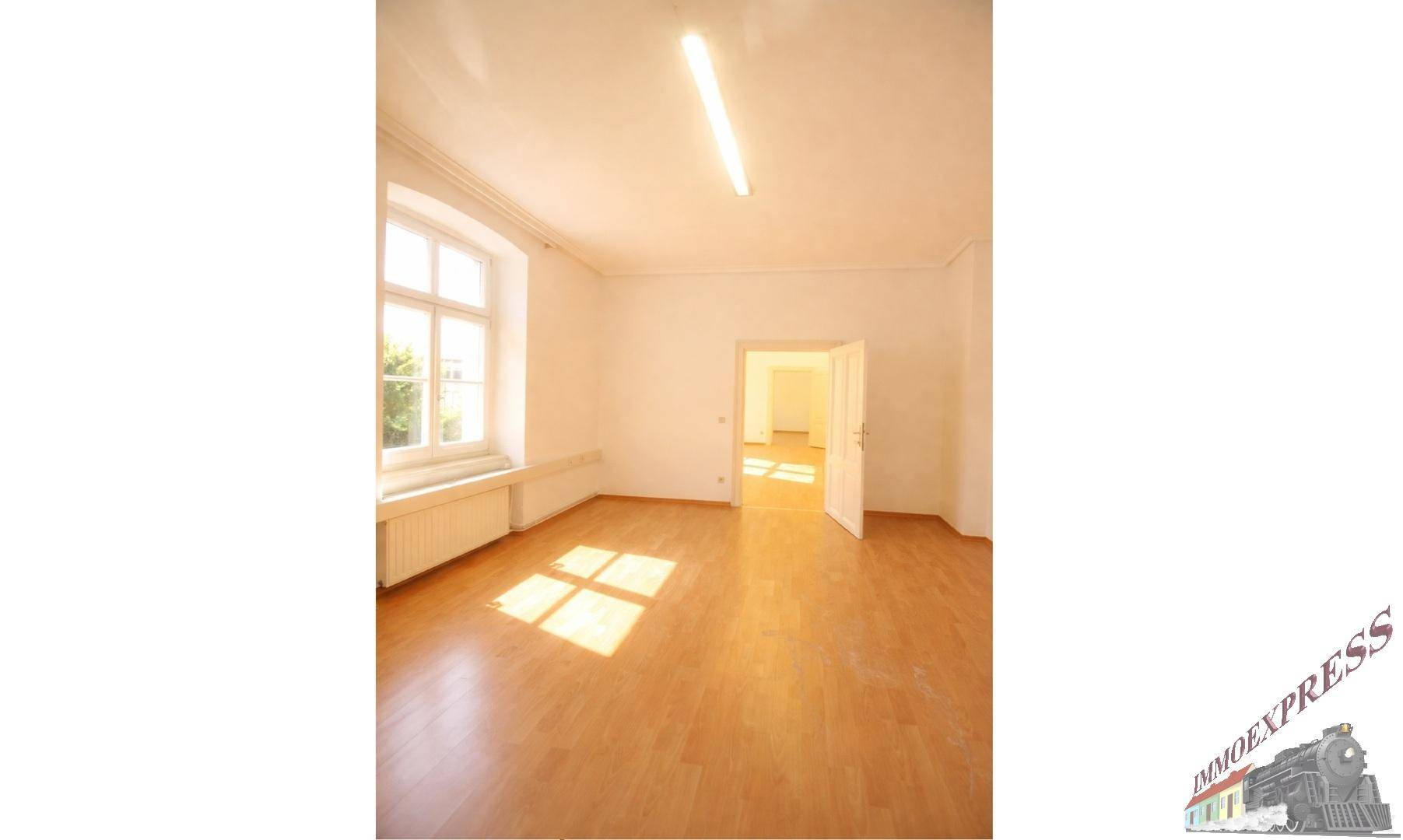 Heller Raum mit Laminatboden und großem Fenster, das viel Tageslicht hereinlässt, bereit zur Einrichtung.