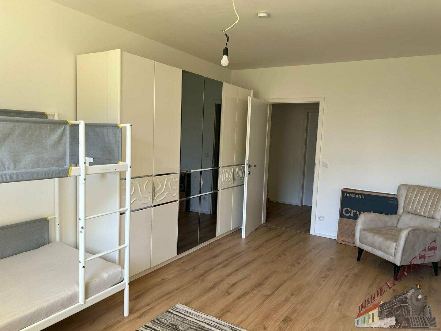 Geräumiges Schlafzimmer mit Etagenbett, großem Kleiderschrank und einem bequemen Sessel.