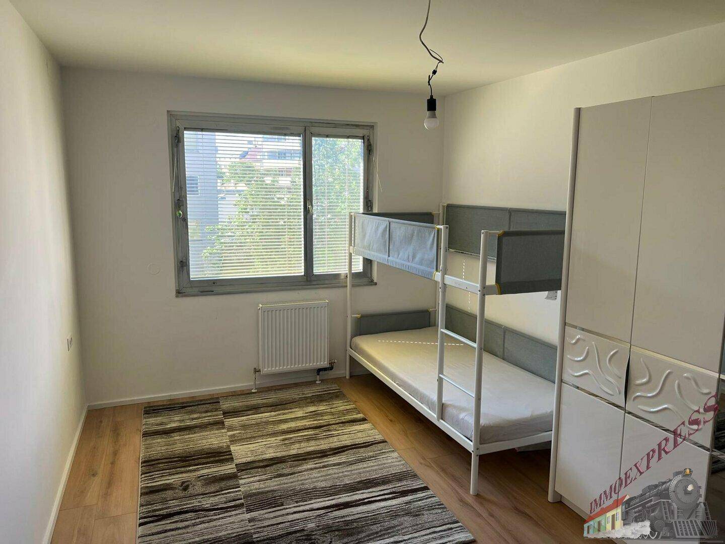 Kinderzimmer mit Etagenbett, großem Fenster mit Jalousien und einem modernen Kleiderschrank.