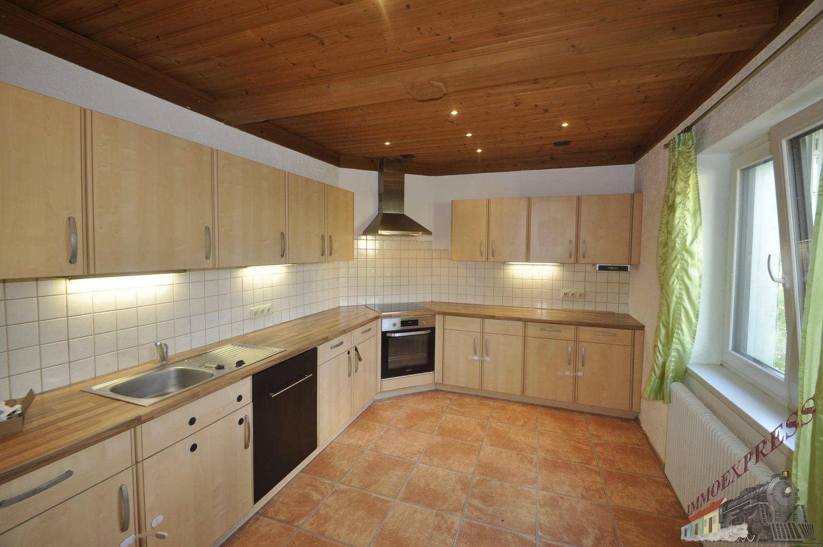 Helle Küche mit Holzdecke, Einbauschränken und Terrakotta-Fliesenboden.