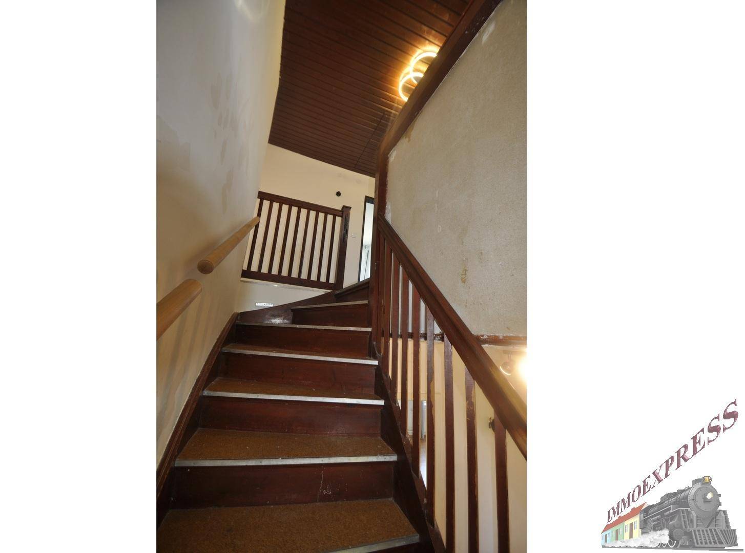 Holztreppe führt in die obere Etage, mit dunkler Holzdecke und Geländer.