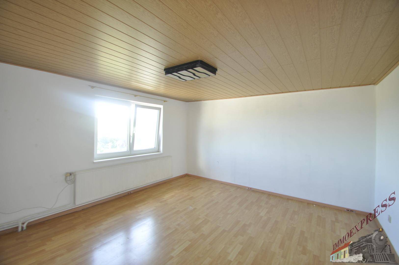Helles Schlafzimmer mit Laminatboden, Holzdecke und großem Fenster.