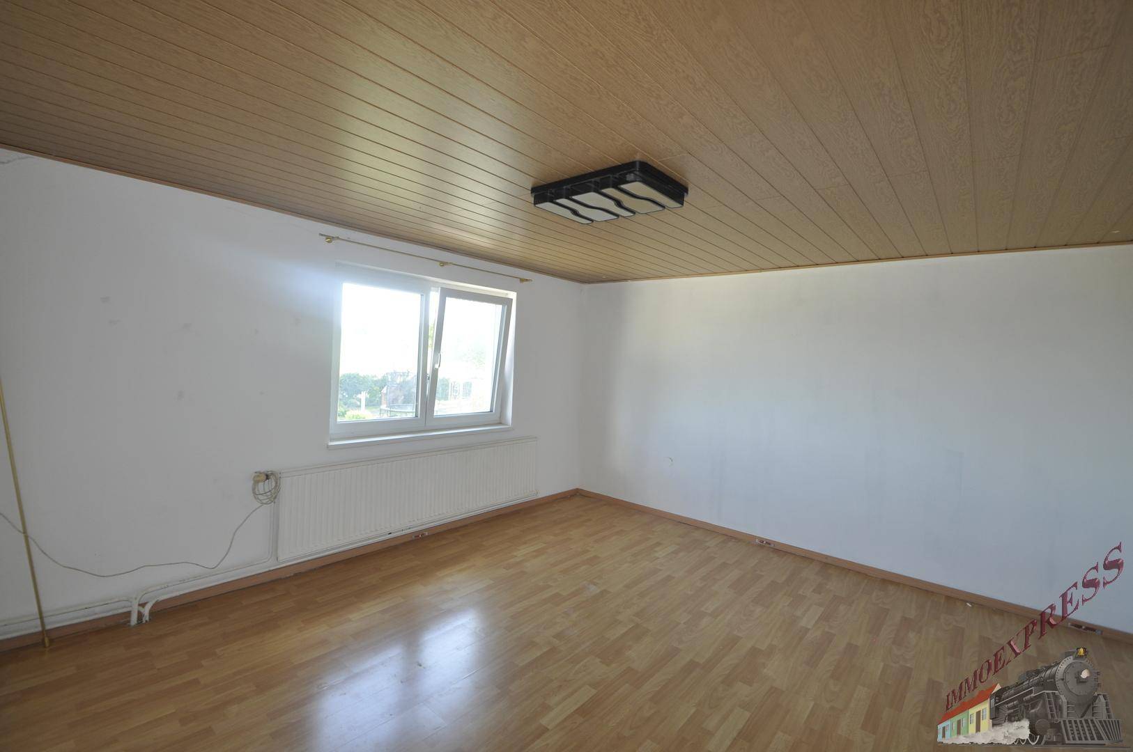 Geräumiges Schlafzimmer mit Laminatboden, Holzdecke und viel Tageslicht.