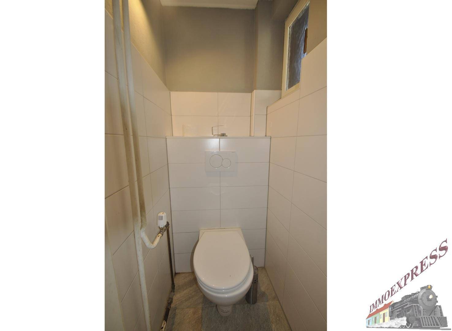 Kleiner Toilettenraum mit WC, gefliesten Wänden und einem kleinen Fenster für Belüftung.
