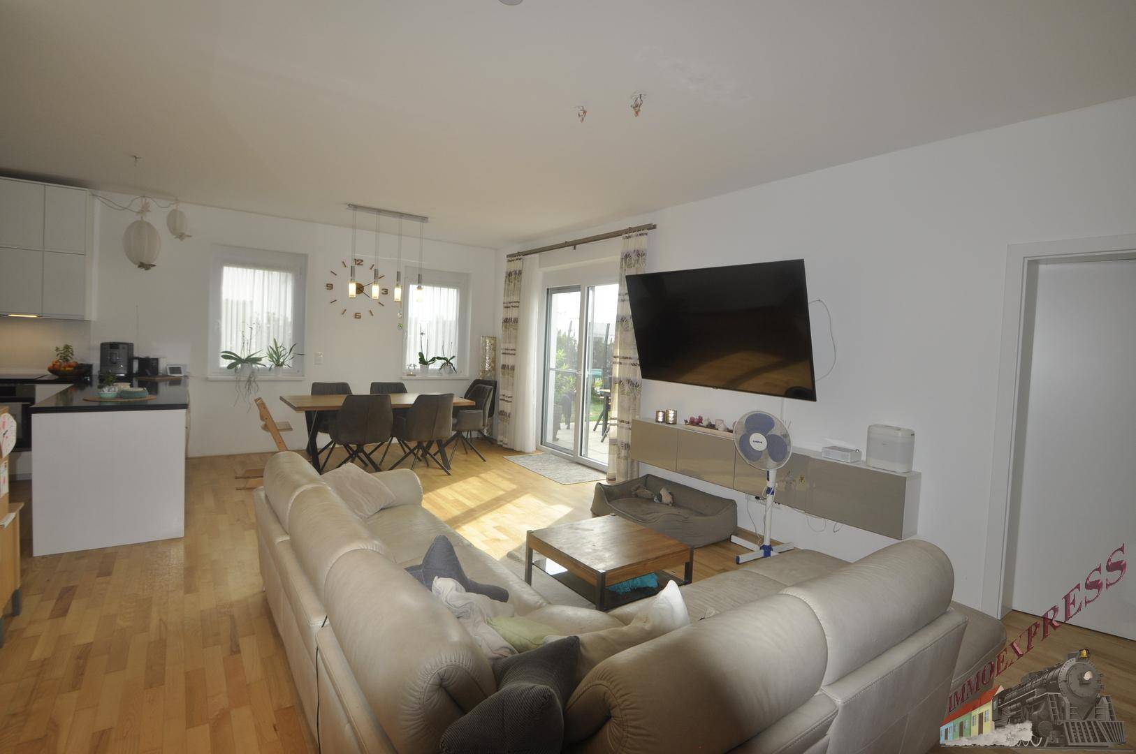 Gemütliches Wohnzimmer mit Sofa, Fernseher und Zugang zur Terrasse.