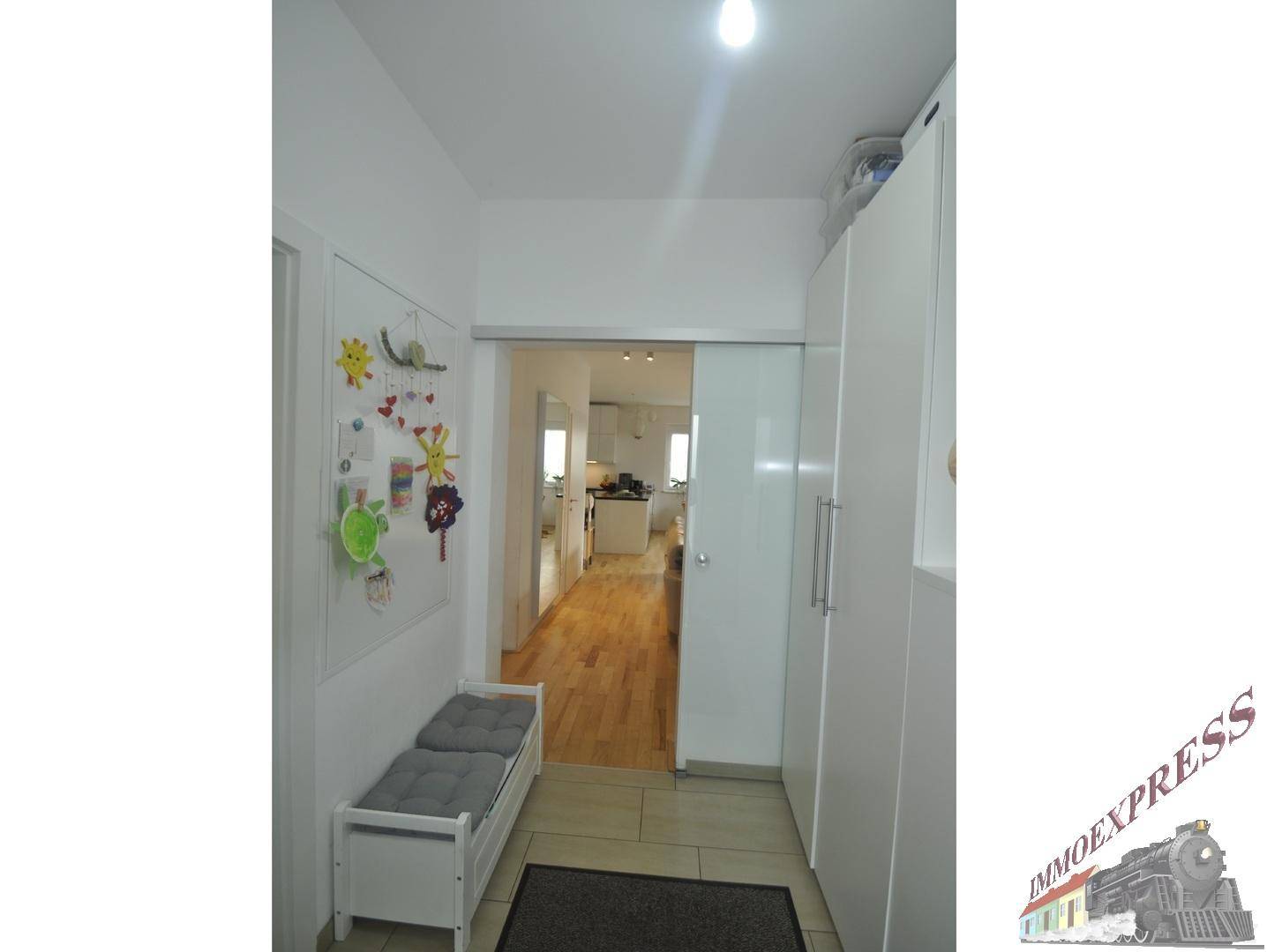 Heller Flur mit Garderobe, Sitzbank und Schiebetür zu den Wohnbereichen.