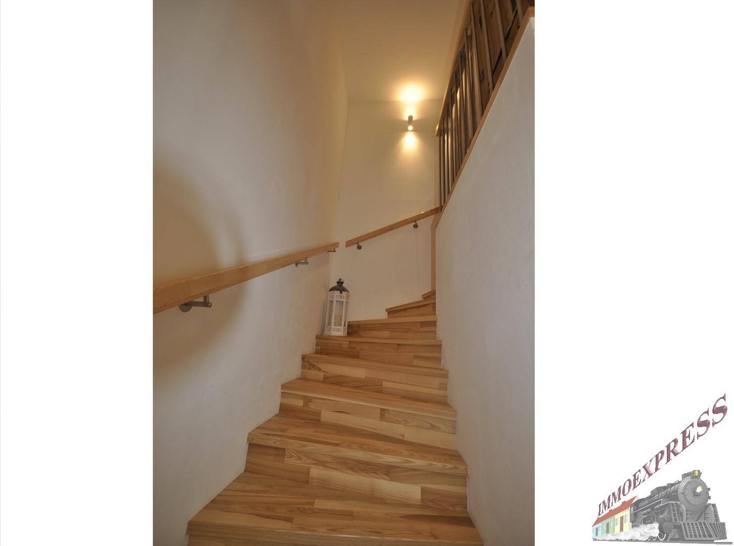 Elegante Holztreppe mit hellem Geländer, die die verschiedenen Etagen verbindet.