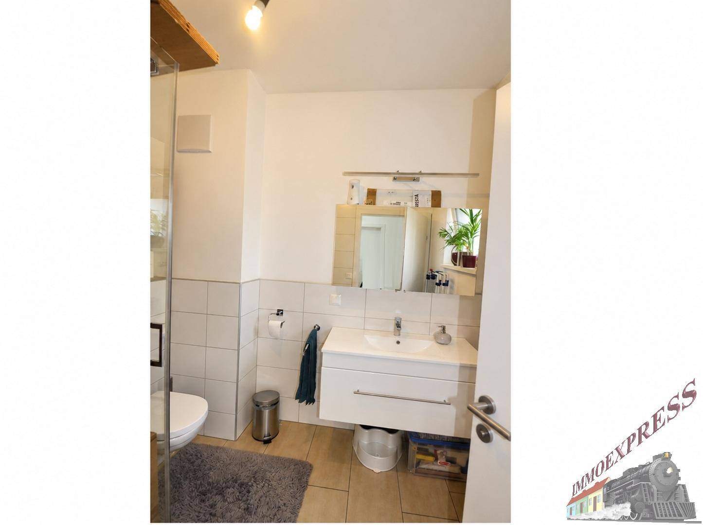 Modernes Badezimmer mit Waschtisch, Spiegel und Duschbereich.