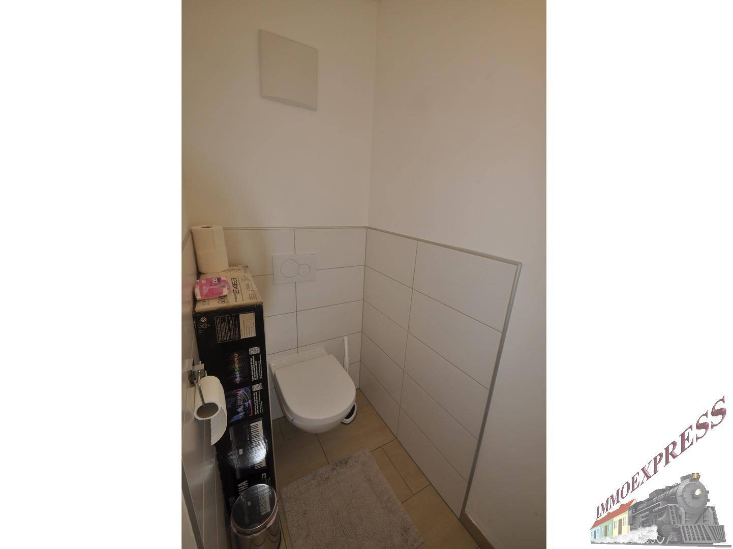 Kleines Gäste-WC mit wandhängendem WC und Fliesen an den Wänden.