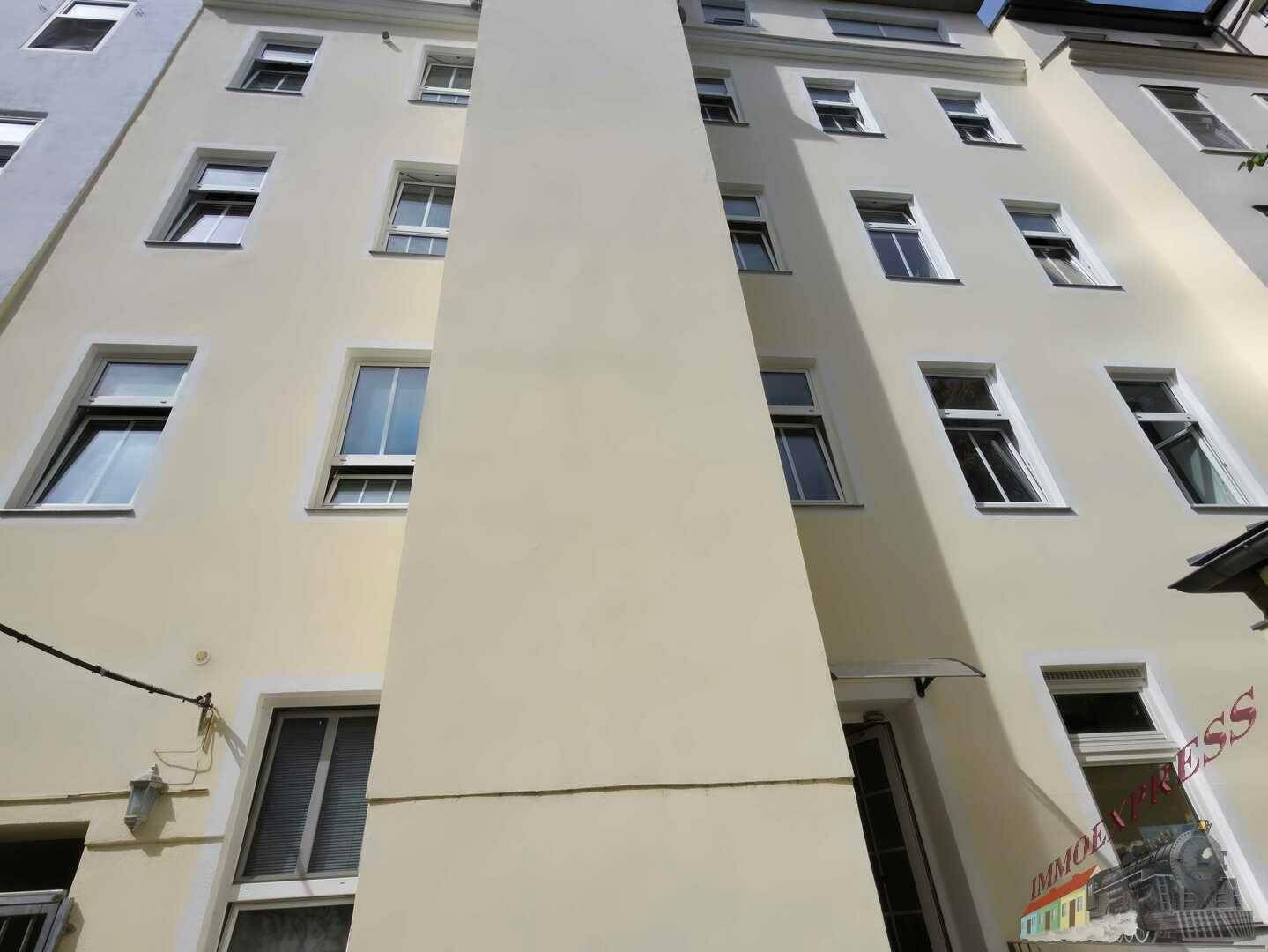 Hohe Fassade eines Wohngebäudes mit vielen Fenstern und schmaler Bauweise.