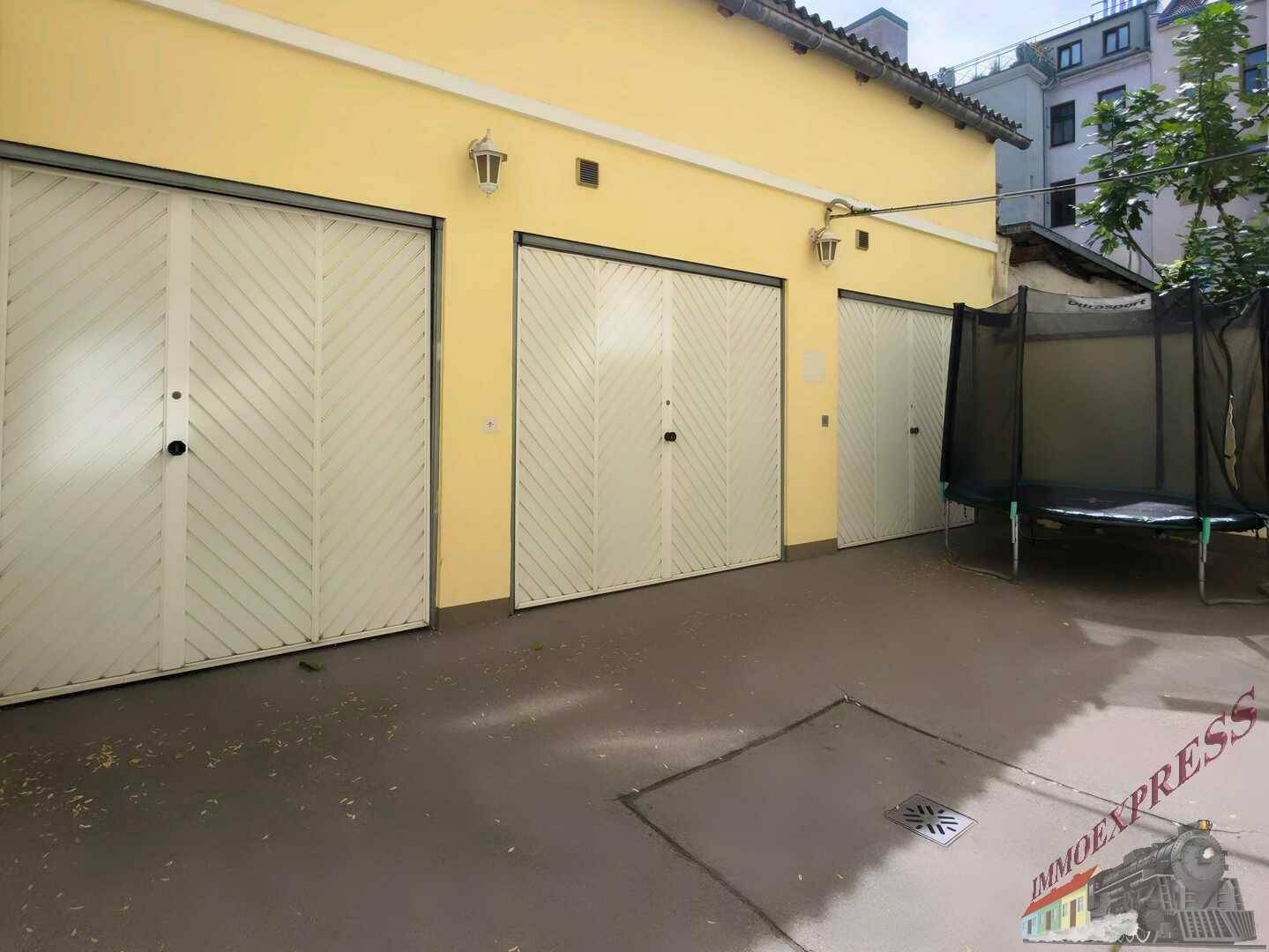 Mehrere Garagentore an einem Gebäude mit einem Trampolin im Hofbereich.