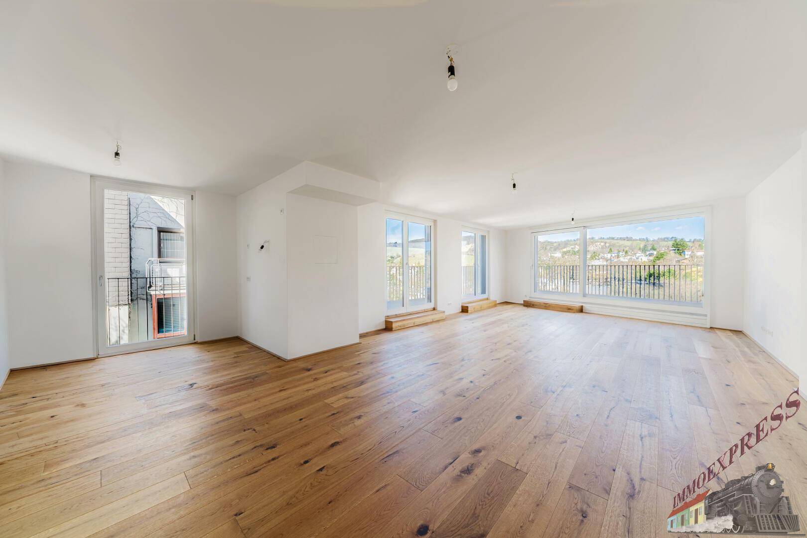 Weitläufiges Wohnzimmer mit Eichenparkett und mehreren Zugängen zu Balkonen mit Aussicht.