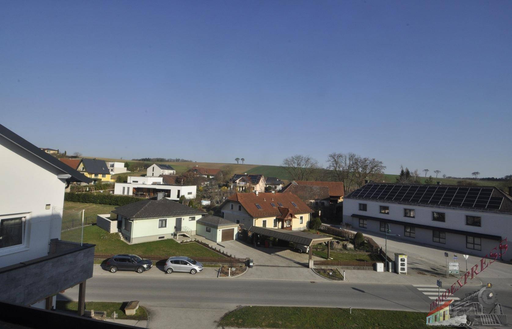 Weitblick über eine ländliche Wohnsiedlung mit Feldern und Solaranlagen auf Dächern.