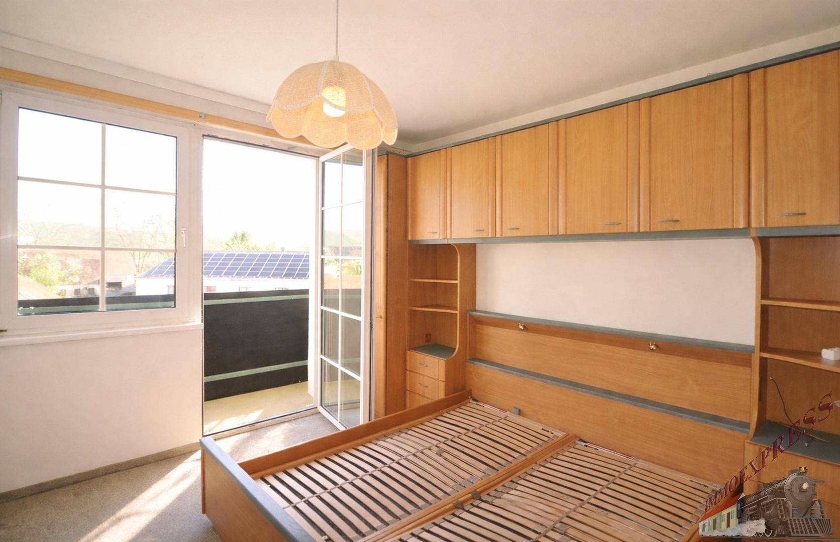 Schlafzimmer mit Einbauschränken aus Holz und direktem Zugang zu einem Balkon.