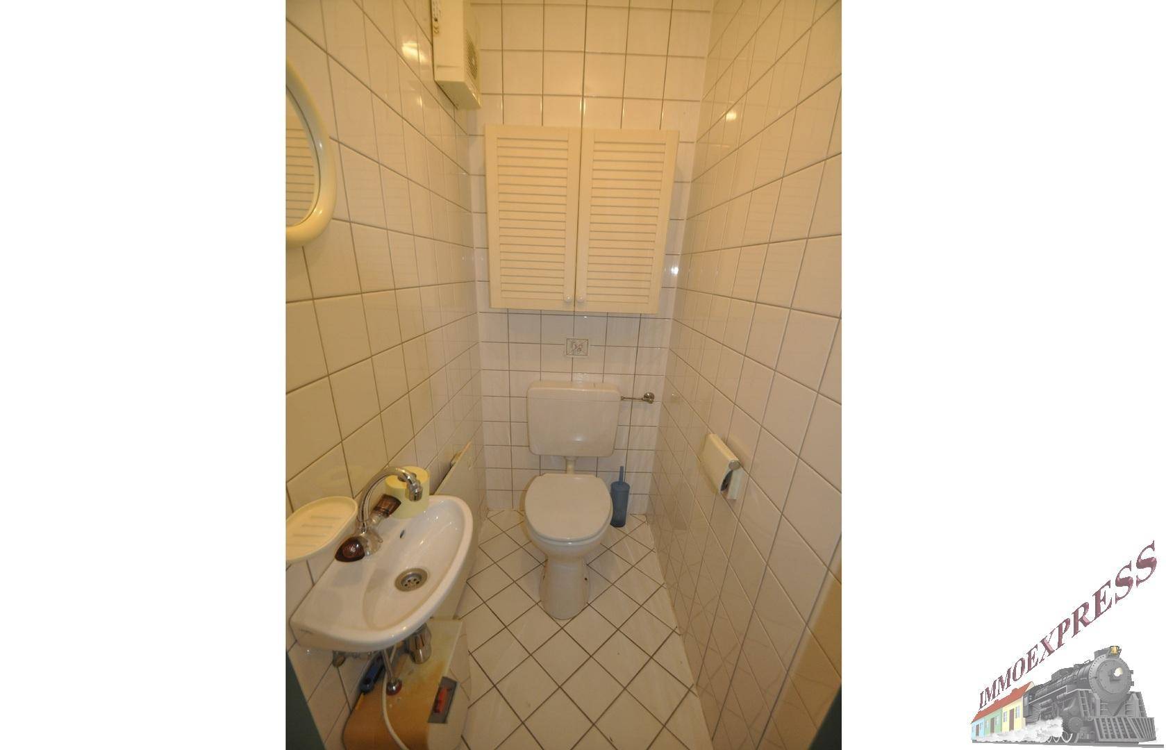 Kleines Gäste-WC mit Toilette und Handwaschbecken, vollständig gefliest.