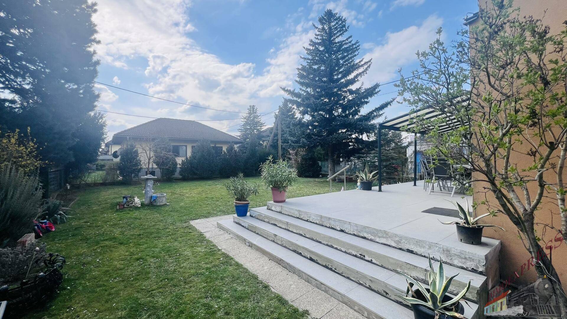 Gepflegter Garten mit Rasenfläche, Terrasse und altem Baumbestand.