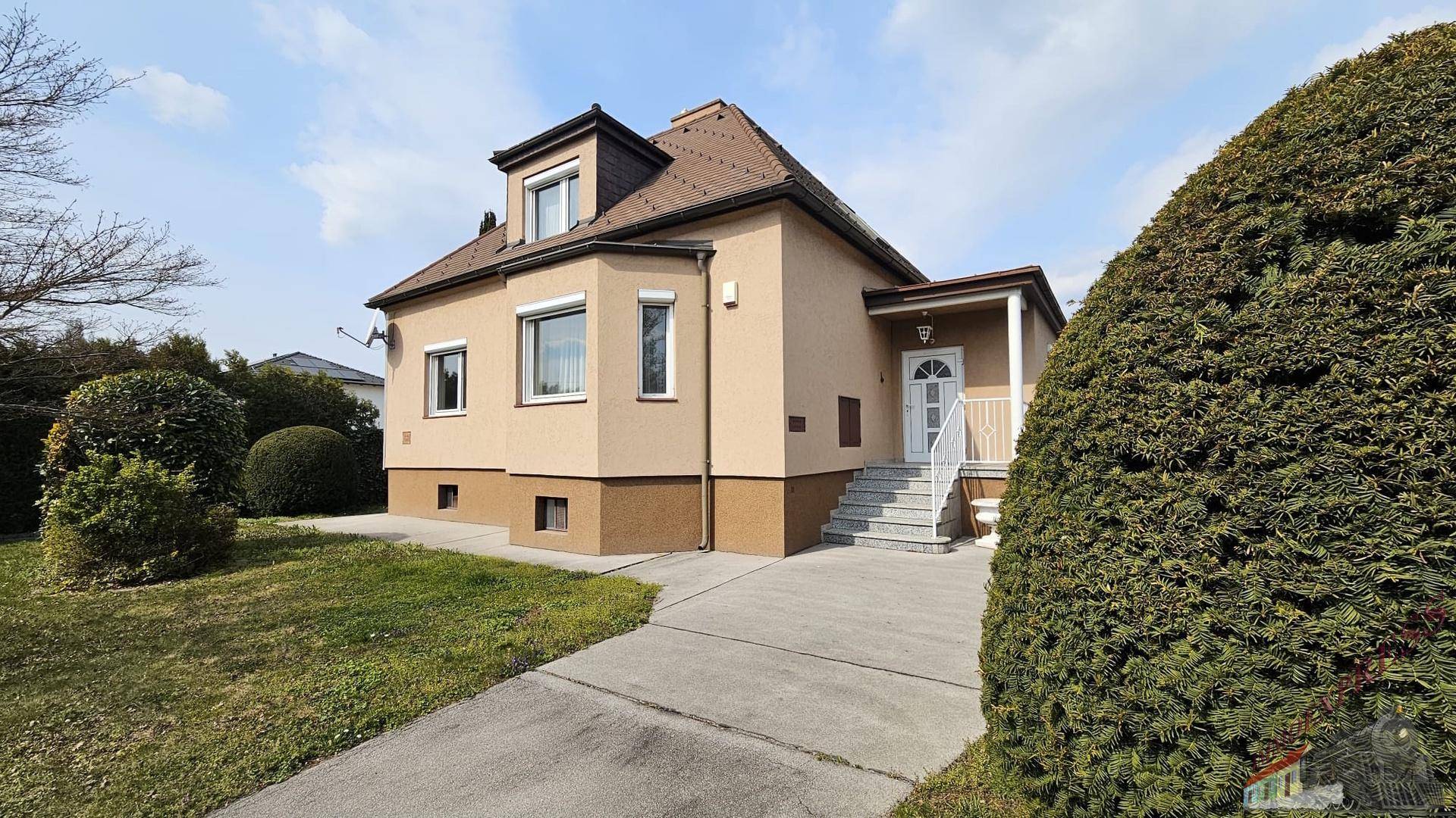 Das Einfamilienhaus von vorne mit gepflegtem Vorgarten, Zufahrt und Eingangstreppe.