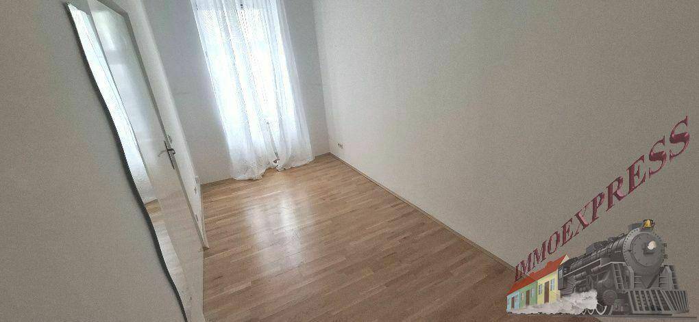 Helles Wohnzimmer mit Holzboden und einem großen Spiegel, der den Raum optisch erweitert.