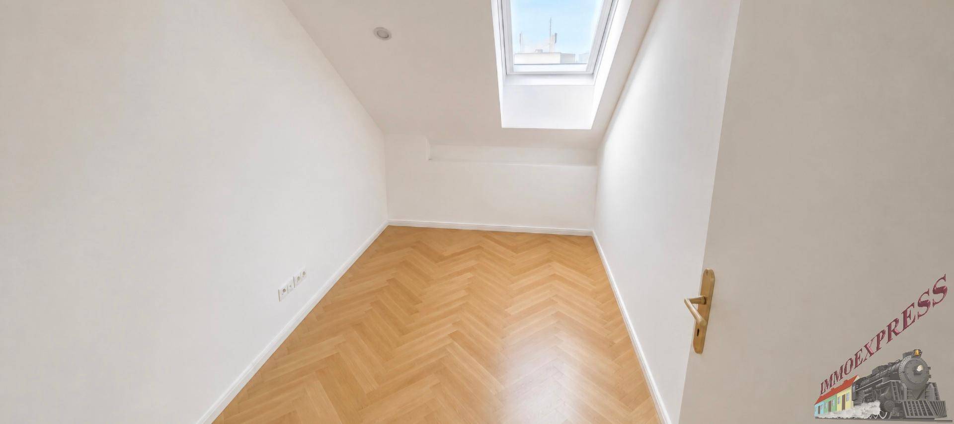 Kleines, helles Zimmer mit Parkettboden und einem Dachfenster, ideal als Kinder- oder Gästezimmer.