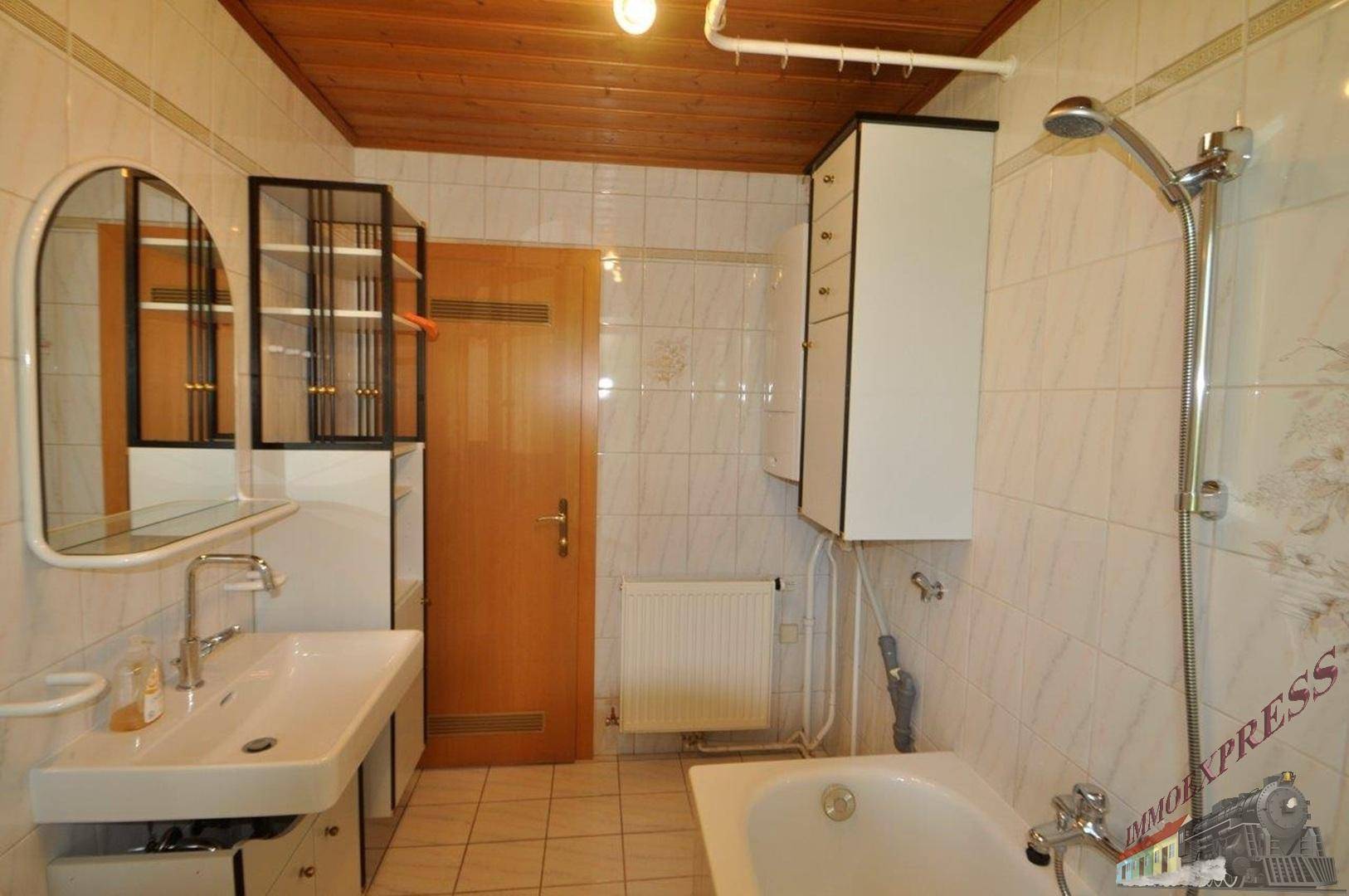 Badezimmer mit Badewanne, Duschkopf, Waschbecken und Spiegelschrank.